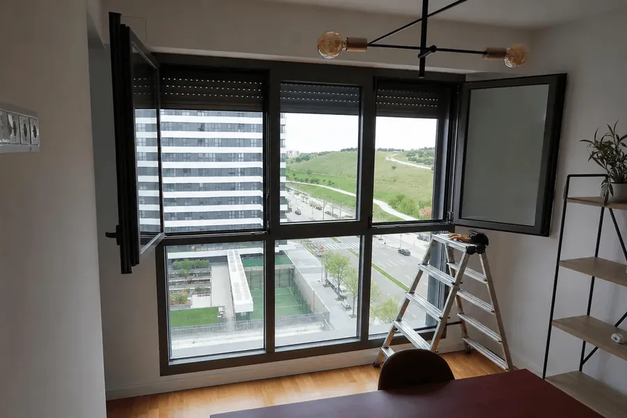 Ventanal con persianas en un piso alto con vistas a la ciudad